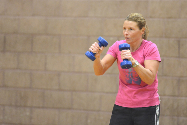 Woman wearing a pink t-shirt holding dumbbells