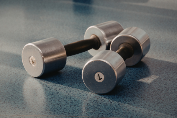 The photographs shows a pair of grey dumbbels on floor