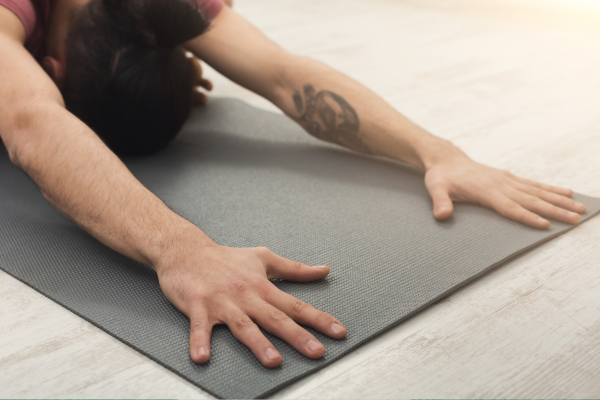 The photograph shows a close up shot of hands on a yoga mat