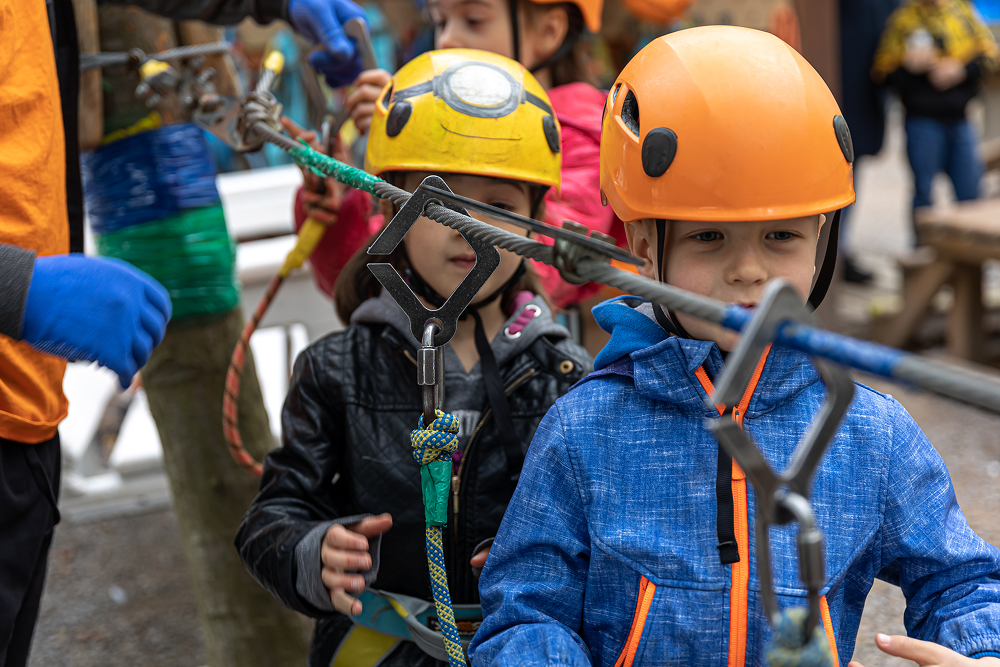 Adventure climbing high wire park - children on course in mountain helmet and safety equipment