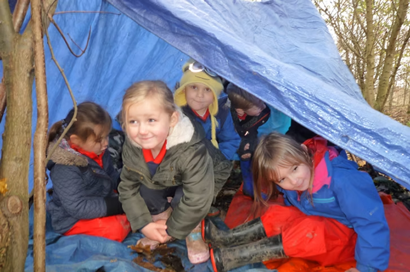 Group of school children inside a den they have built