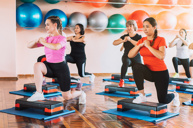 Group of women doing step aerobics indoors