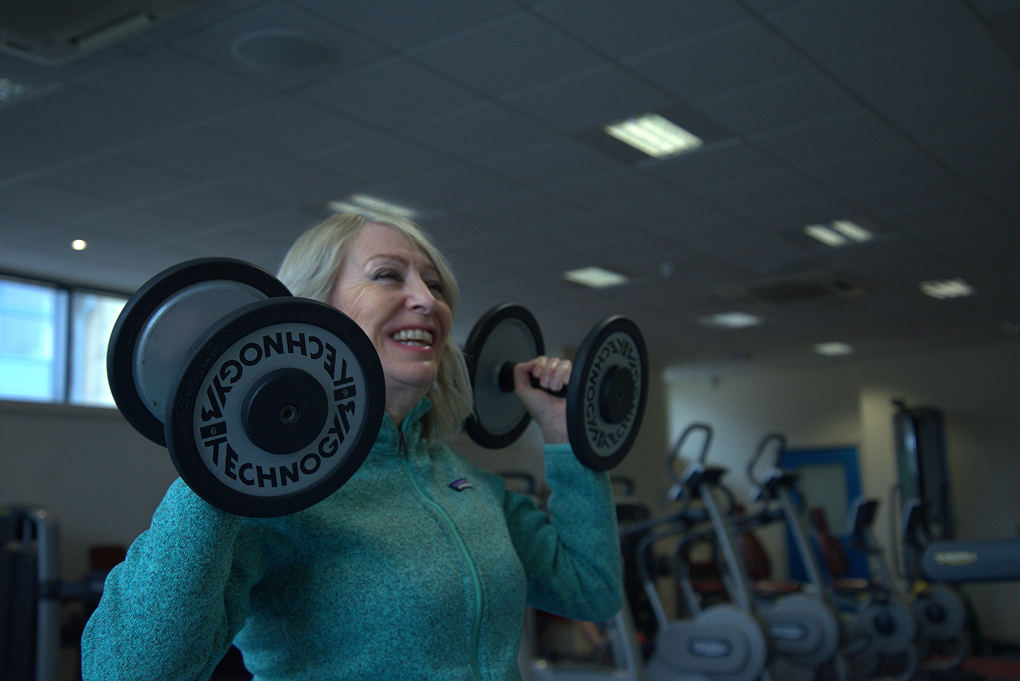 Older lady lifting weights in a gym setting