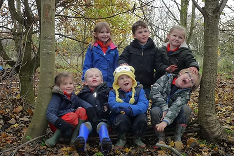 Group of children in a woodland setting all smiling