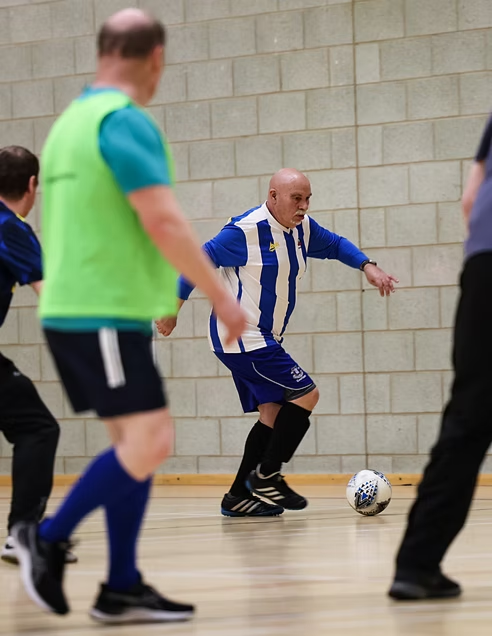 Group of older men playing walking football in a sports hall